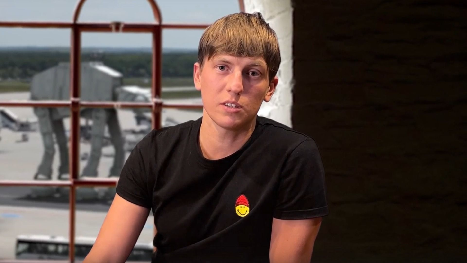 Парень в черной футболке сидит у окна