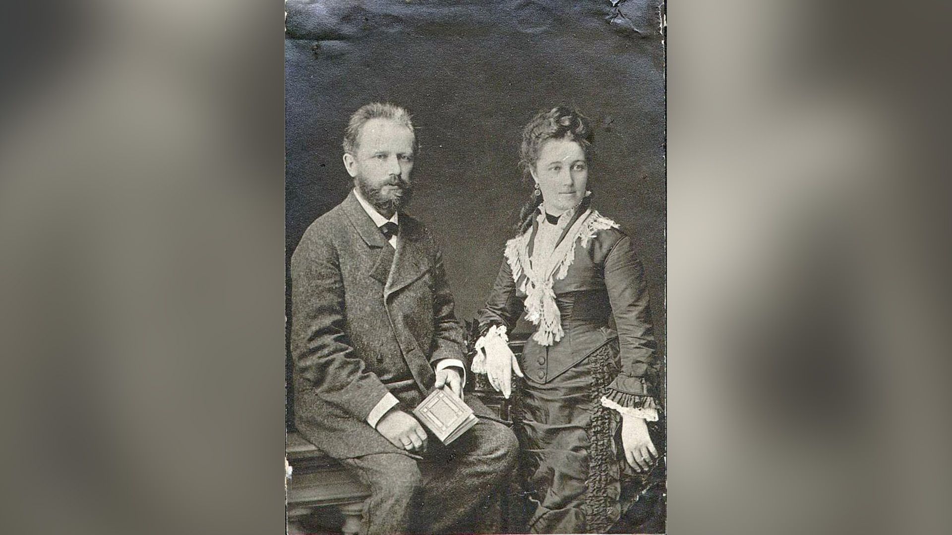 Пётр Чайковский сидит с блокнотом в руке, рядом стоит его жена Антонина Милюкова