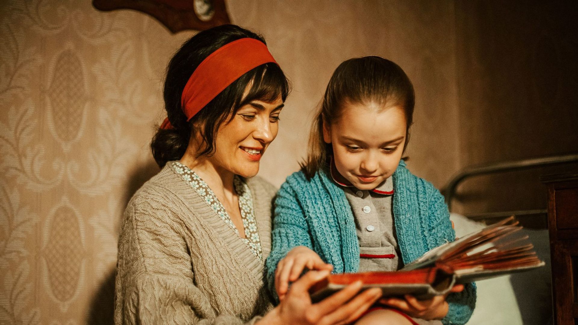 Виктория Полторак с маленькой девочкой сидит на тахте и читает книгу