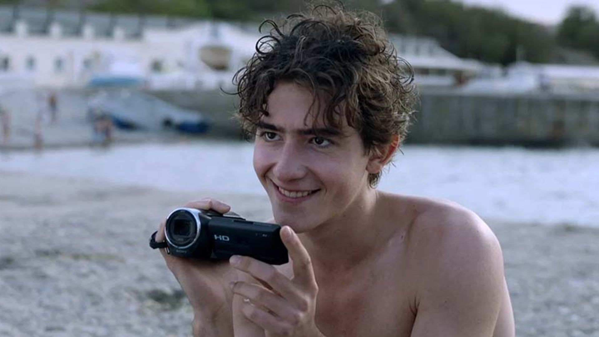 Артём Кошман на пляже держит цифровой фотоаппарат