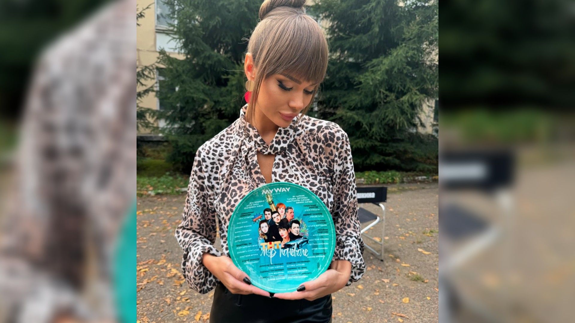 Яна Кошкина с пучком на голове держит в руках бирюзовую тарелку с надписью "мэр поневоле"