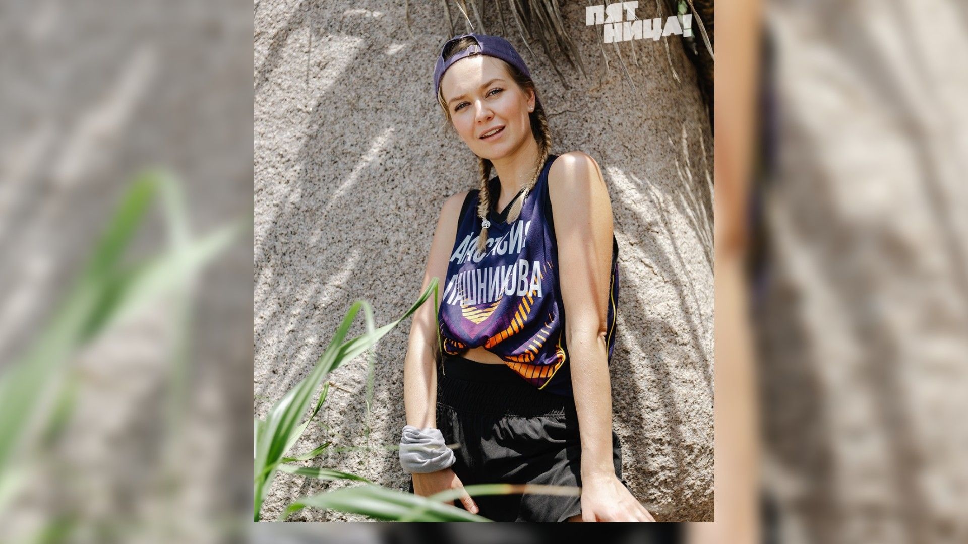 Анастасия Калашникова в майке и кепке на фоне камня
