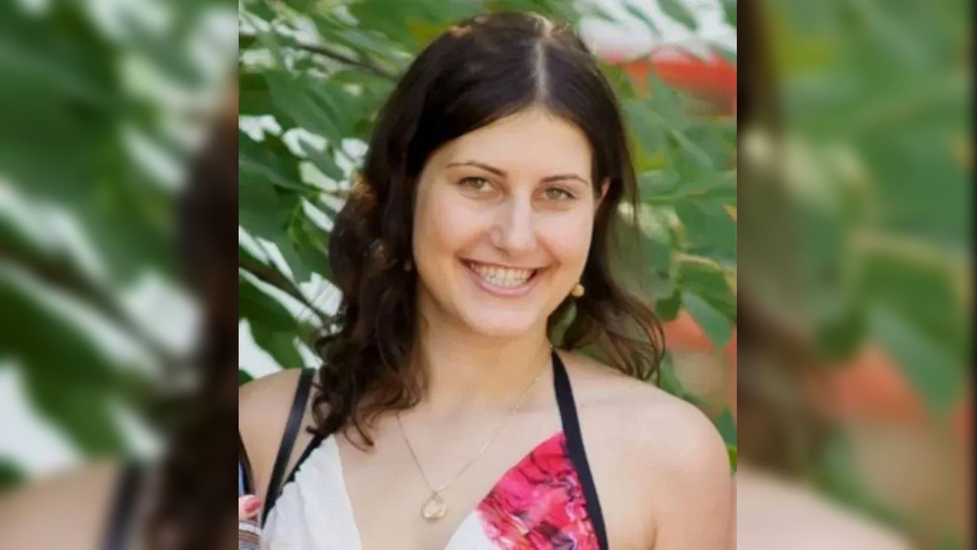 Девушка в платье стоит на фоне льстьев дерева