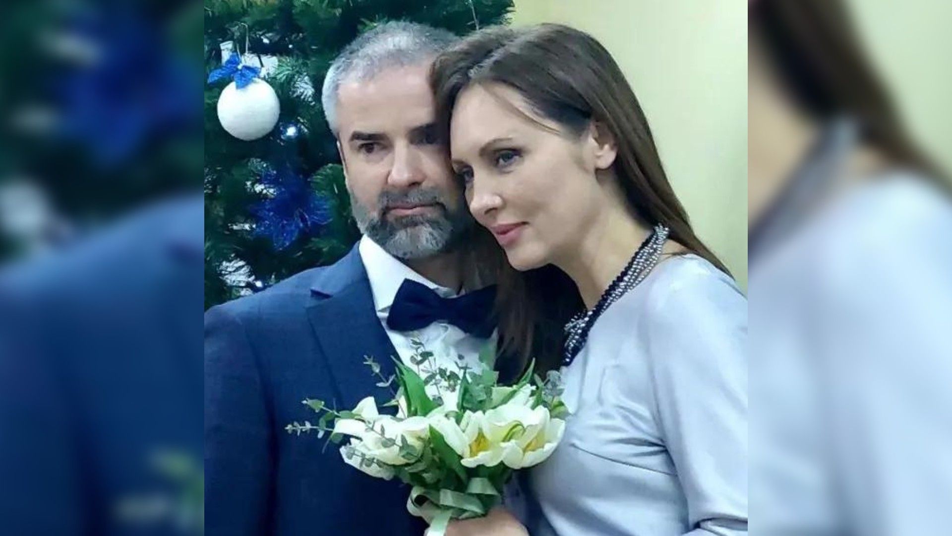 Елена Ксенофонтова и Андрей Куликов позируют у ёлки с букетом цветов