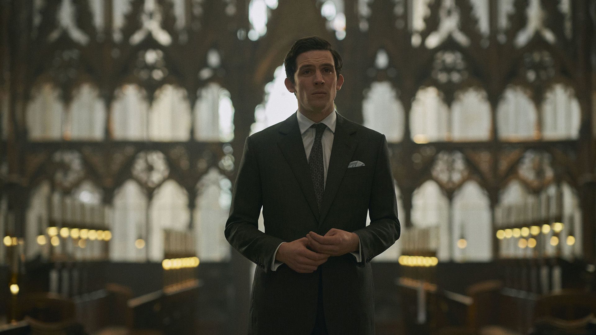 Джош О'Коннор в роли принца Чарльза стоит в церкви на фоне высоких готических окон