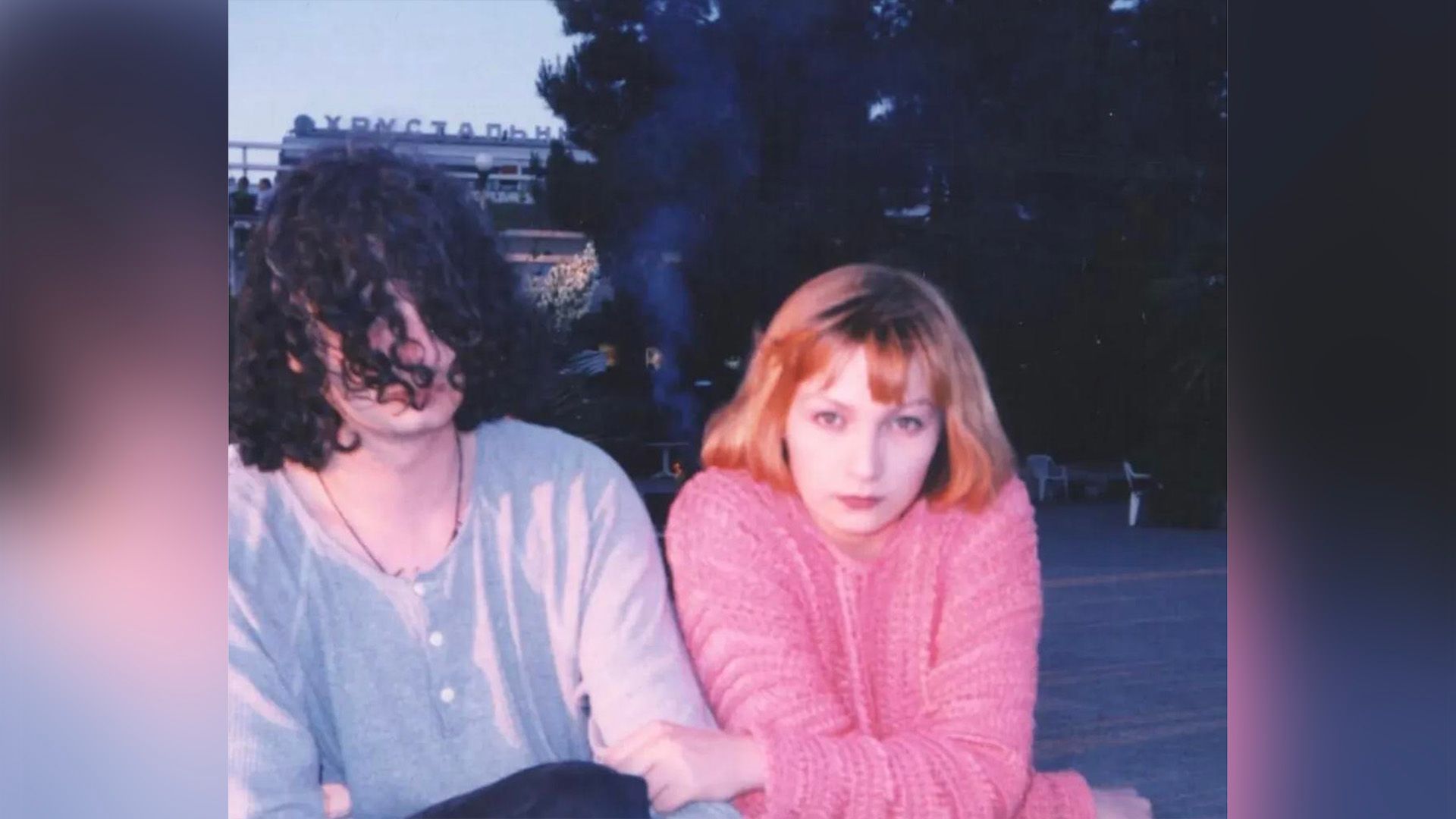 Ксения Качалина в розовом свитере сидит рядом с Алексеем Паперным с длинными кудрявыми волосами