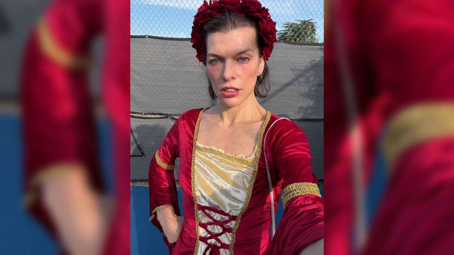 Мила Йовович в красном бархатном средневековом платье делает селфи