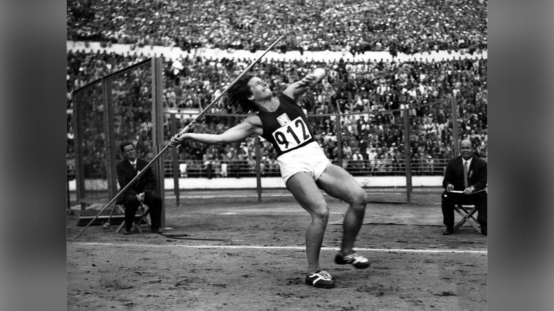 Дана Затопкова в белых шортах и чёрной майке с номером 912 приготовилась метнуть копьё на Олимпийских играх