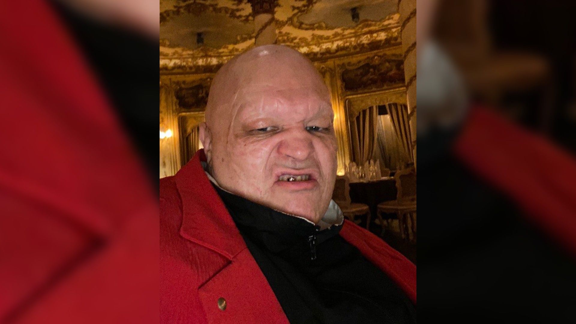 Стас Барецкий в красном пиджаке скалится на камеру