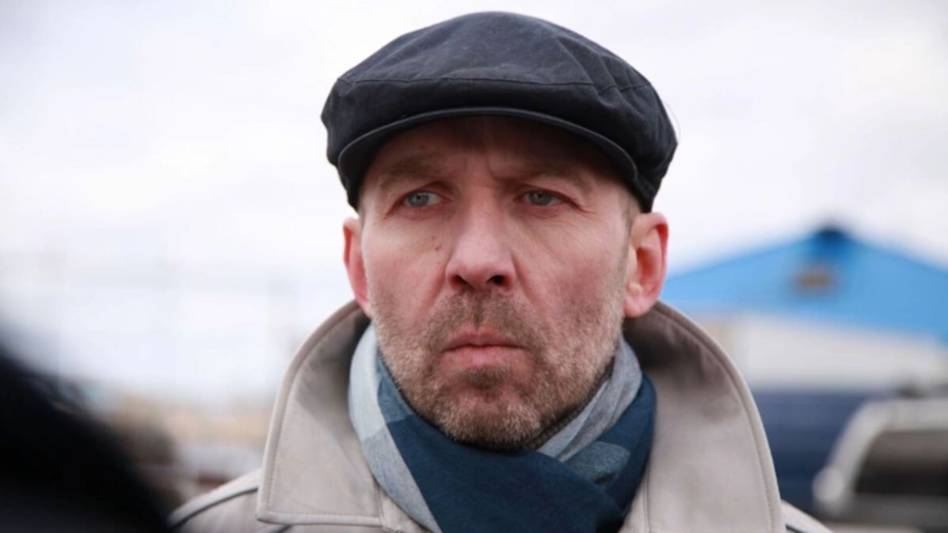 Кирилл Полухин в кепке и плаще, лицо крупным планом