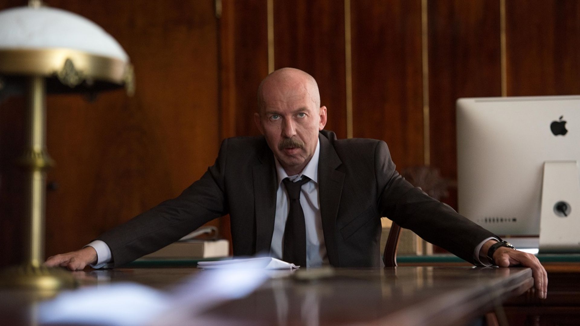 Кирилл Полухин в костюме сидит за рабочим столом