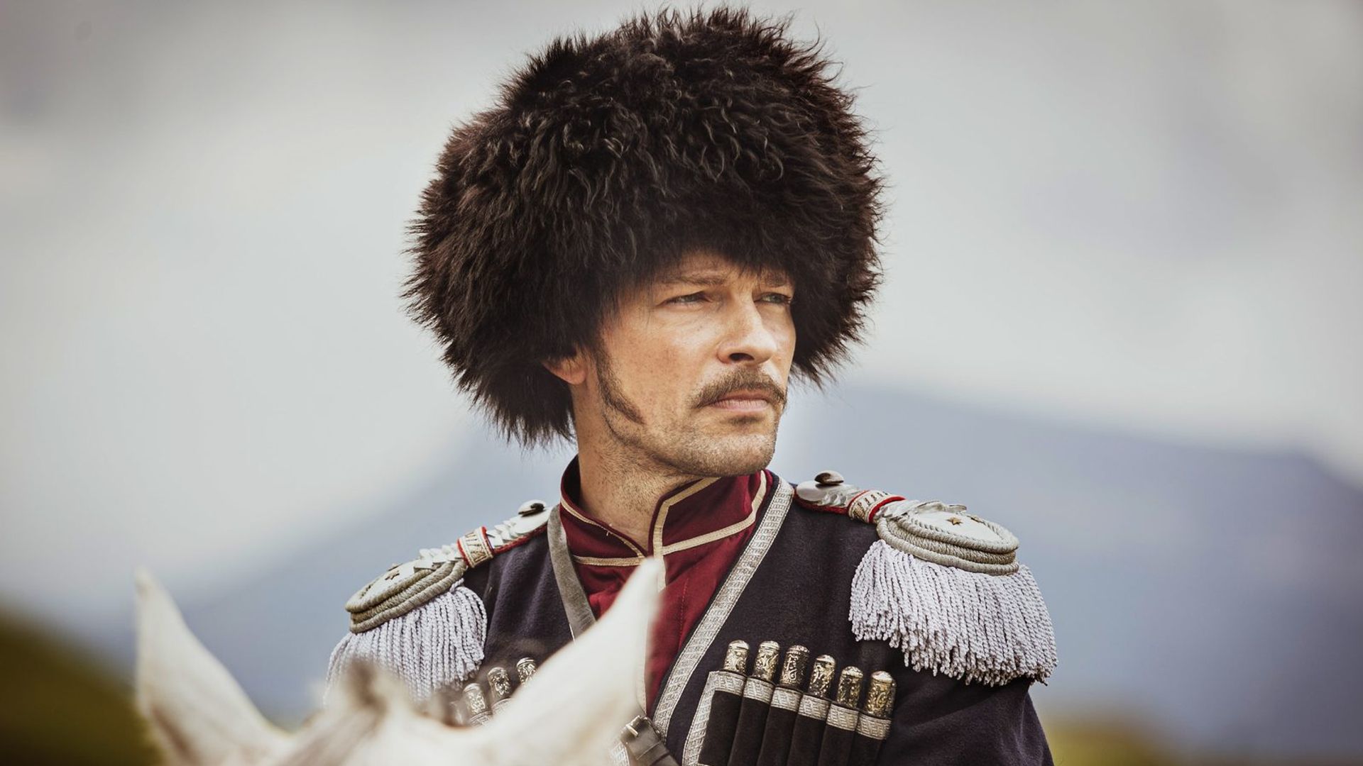 Даниил Страхов в папахе на коне, вид сбоку