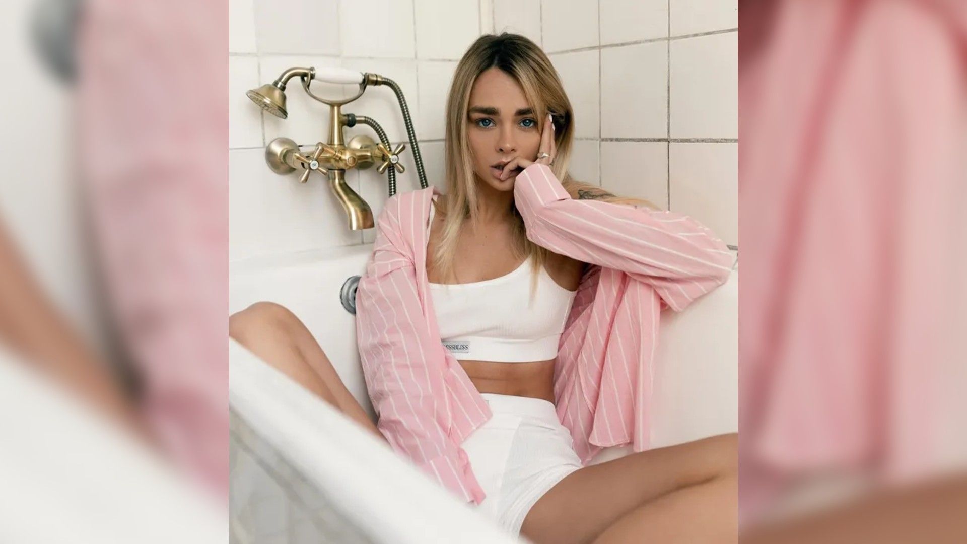 Мария Горячева в белом спортивном костюме и розовой кофте сидит в ванной