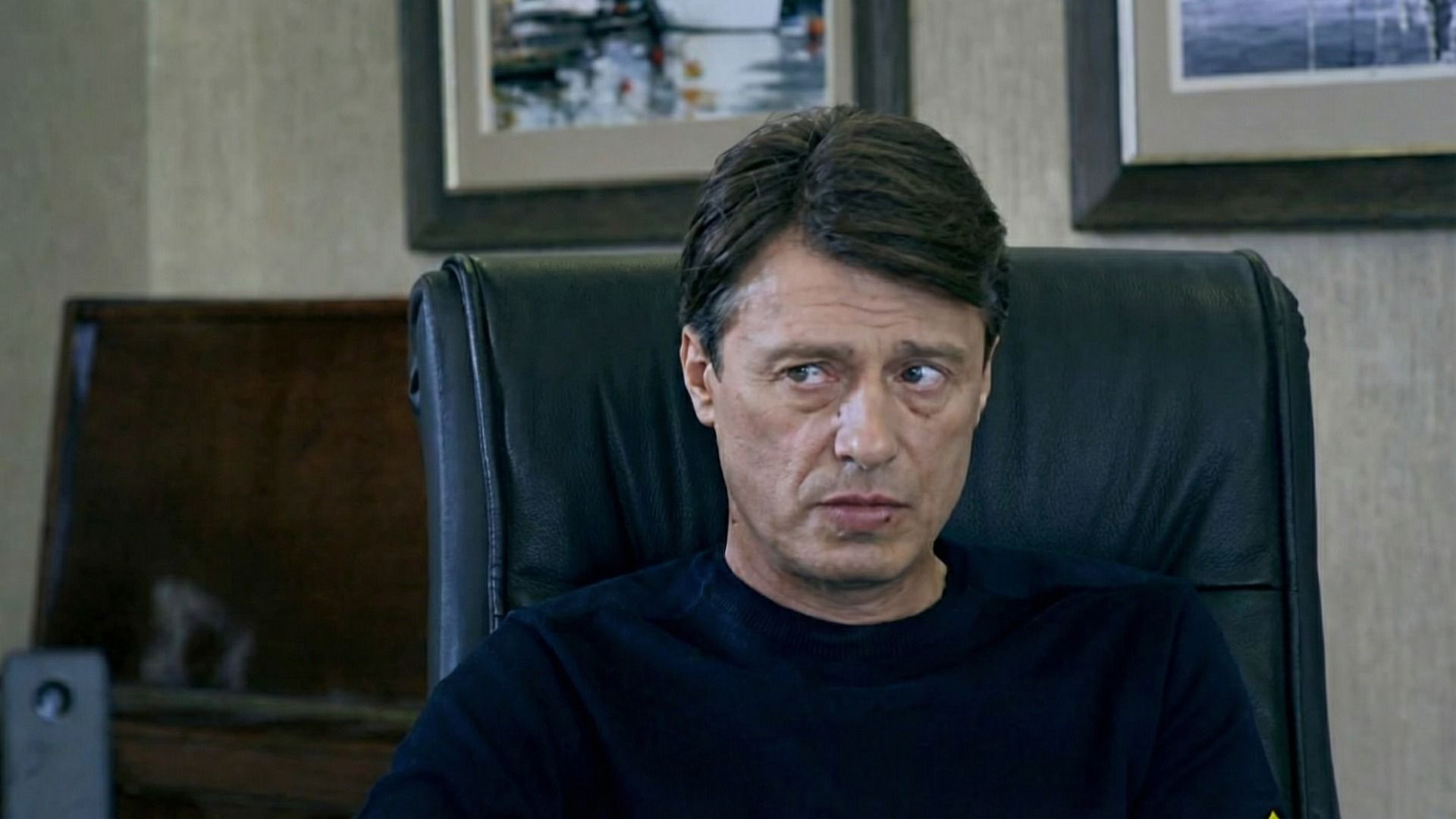 Мужчина в черной кофте сидит на черном кресле