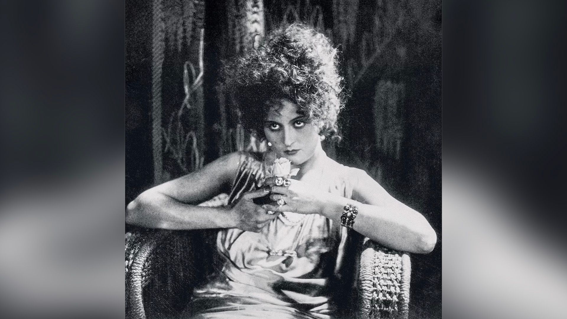 Актриса Вероника Полонская сидит в плетёном кресле с цветком в руках