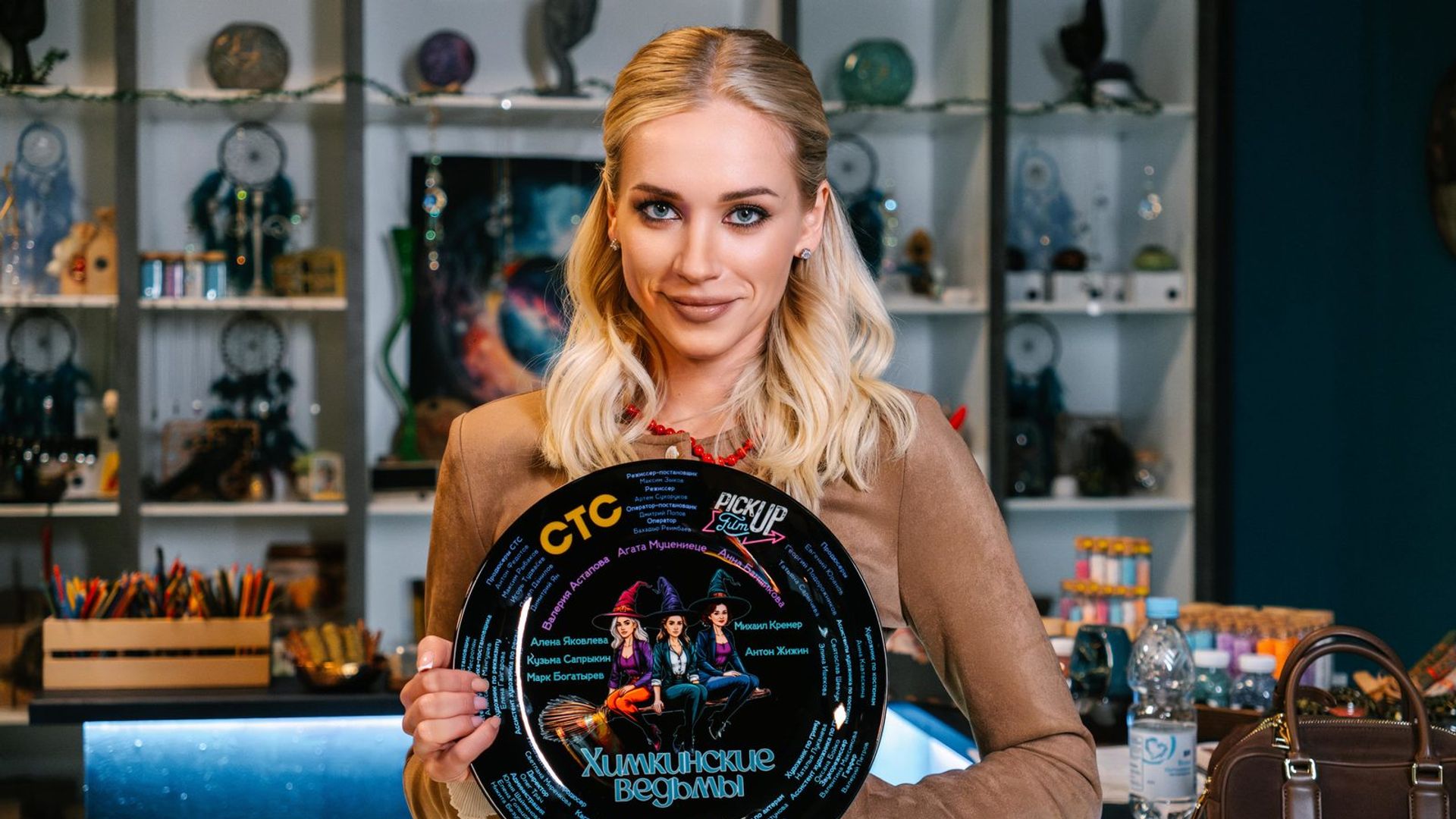 Валерия Астапова стоит и держит в руках тарелку с надписью Химкинские ведьмы