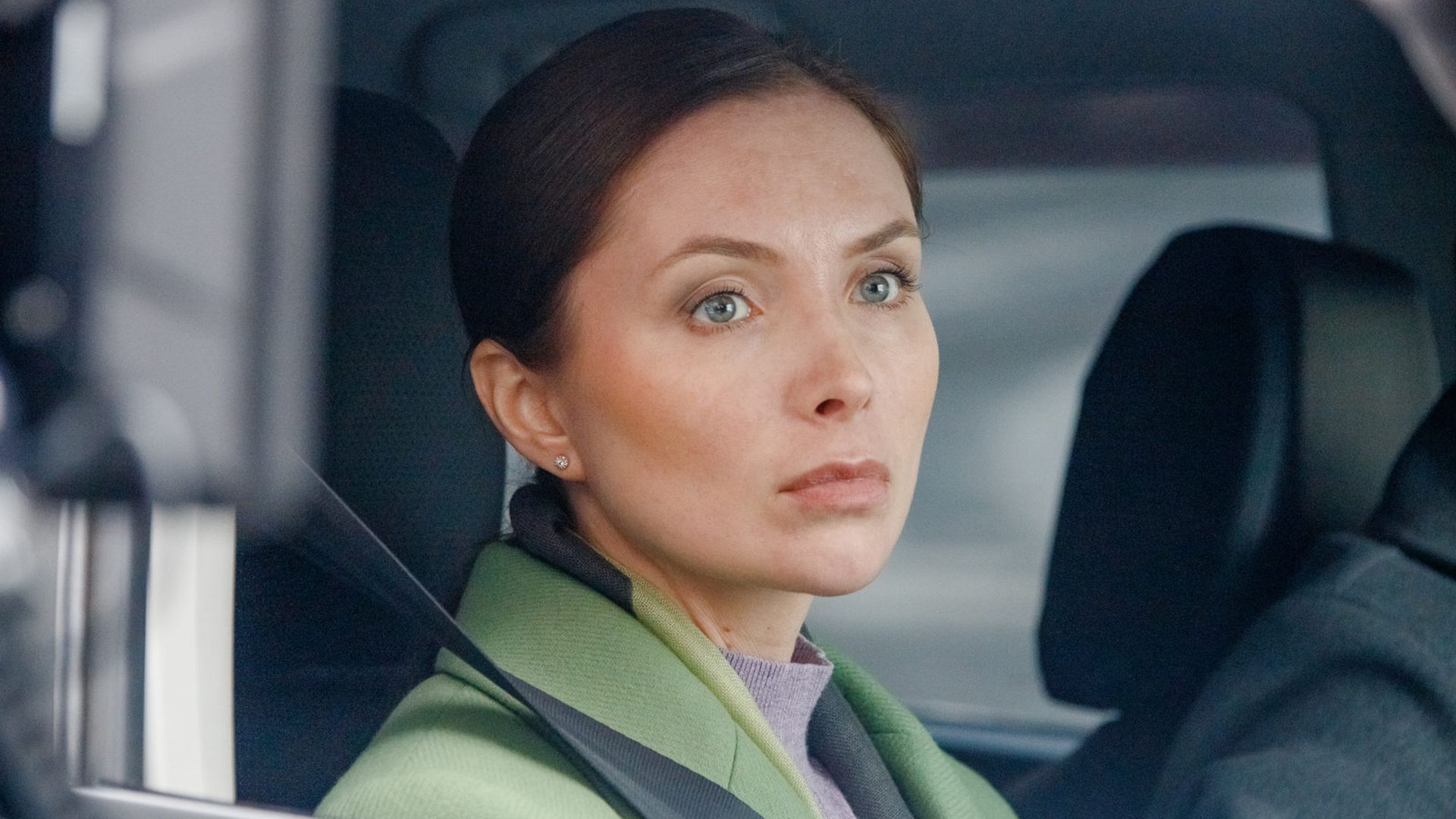 Елена Радевич с убранными в хвост волосами выглядывает из окна автомобиля