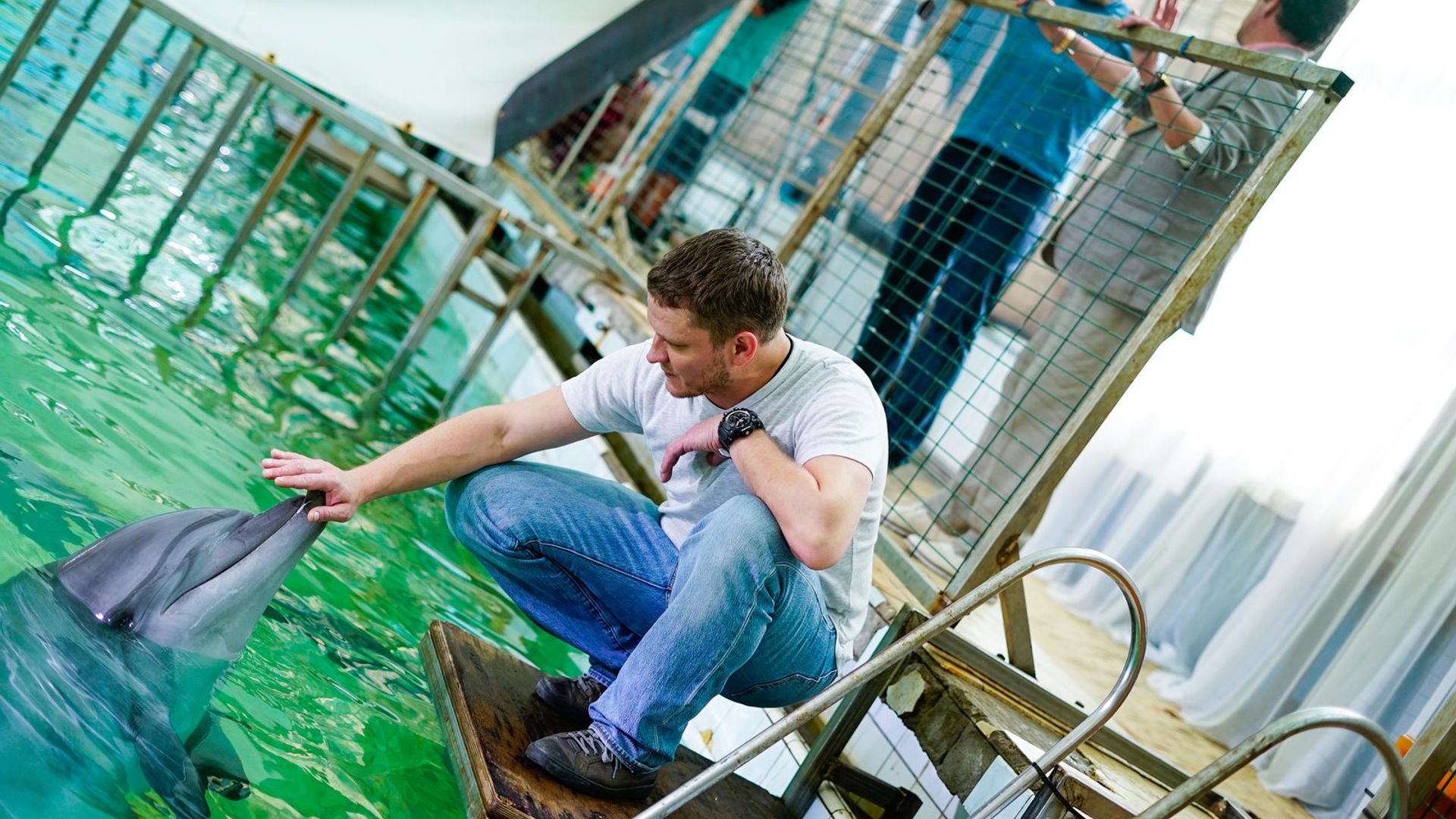 Сергей Жарков гладит дельфина в дельфинарии