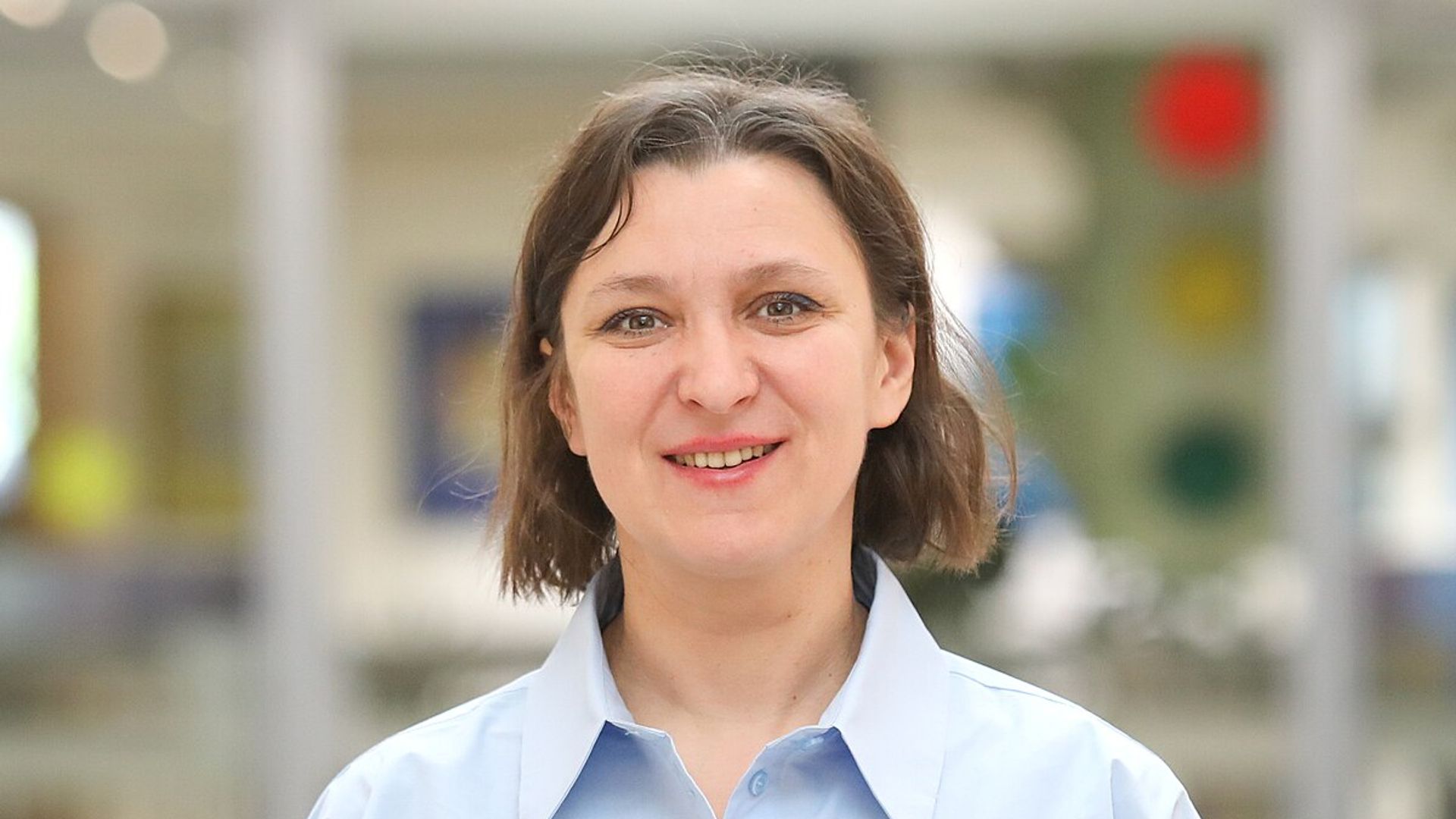 Олеся Железняк смотрит прямо в камеру, у нее каре и нежно-голубая рубашка