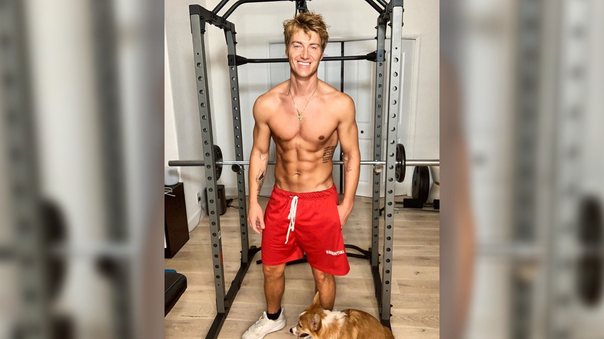 Алексей Воробьёв в красных шортах стоит на фоне тренажёра