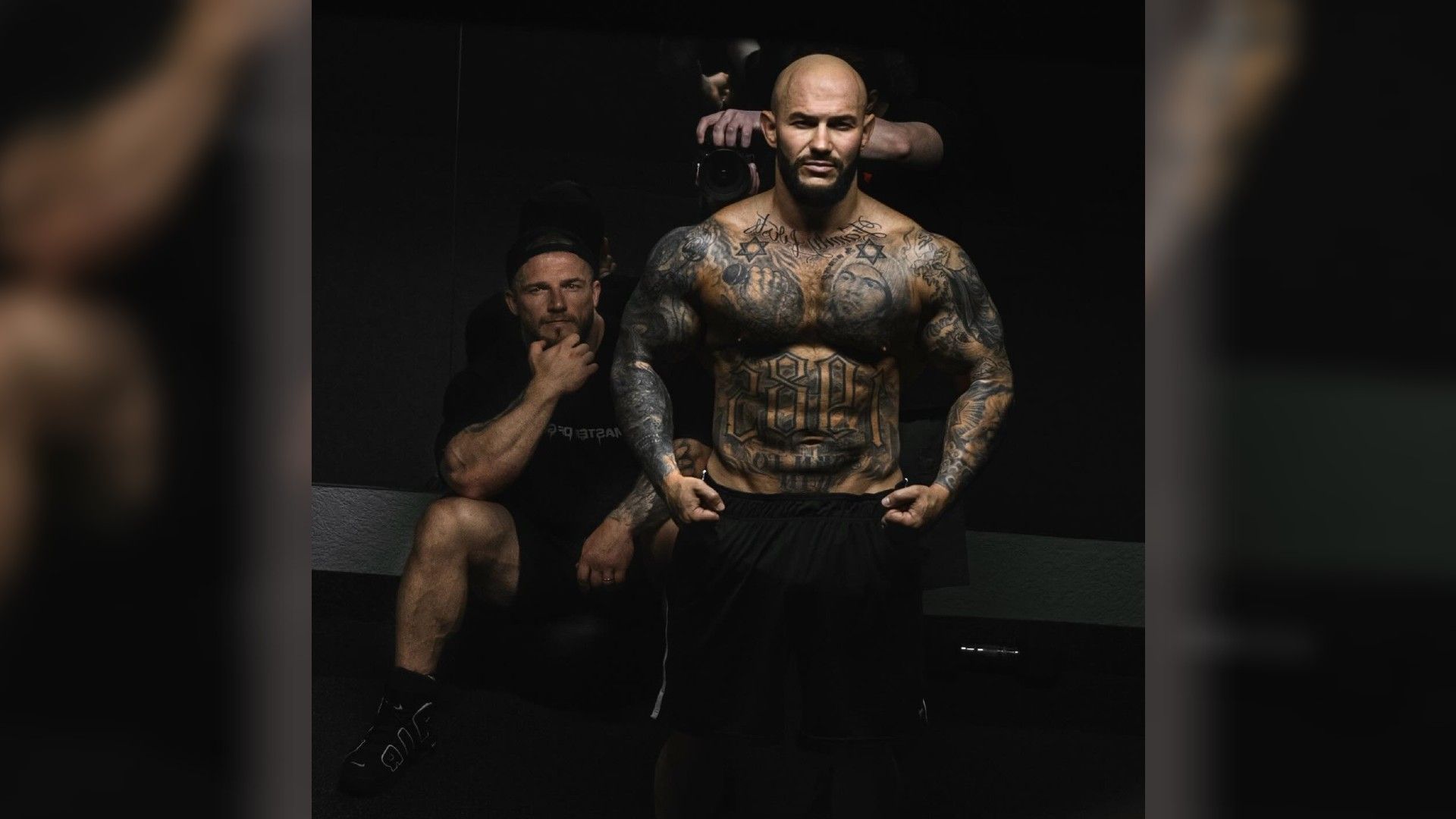 Джиган стоит в бойцовской позе, показывая тело в татуировках