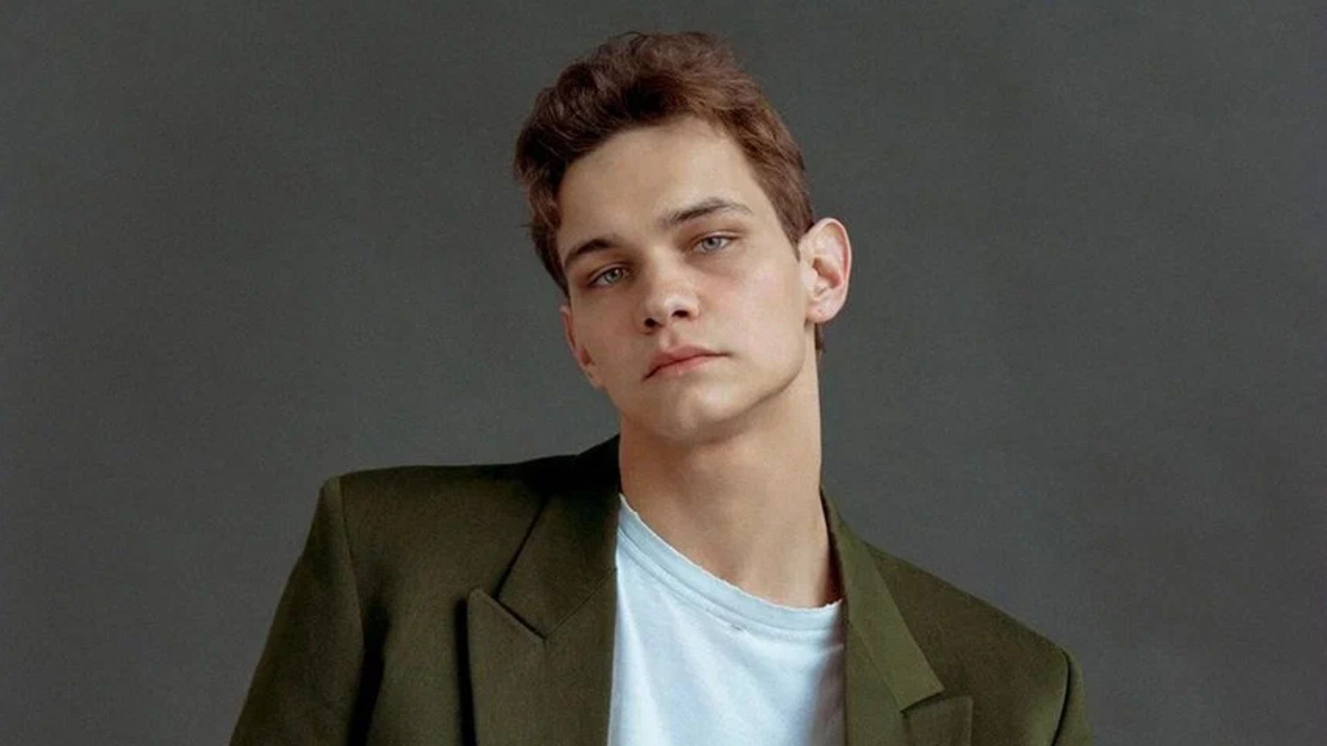 Актер Слава Копейкин сидит на стуле в зеленом пиджаке