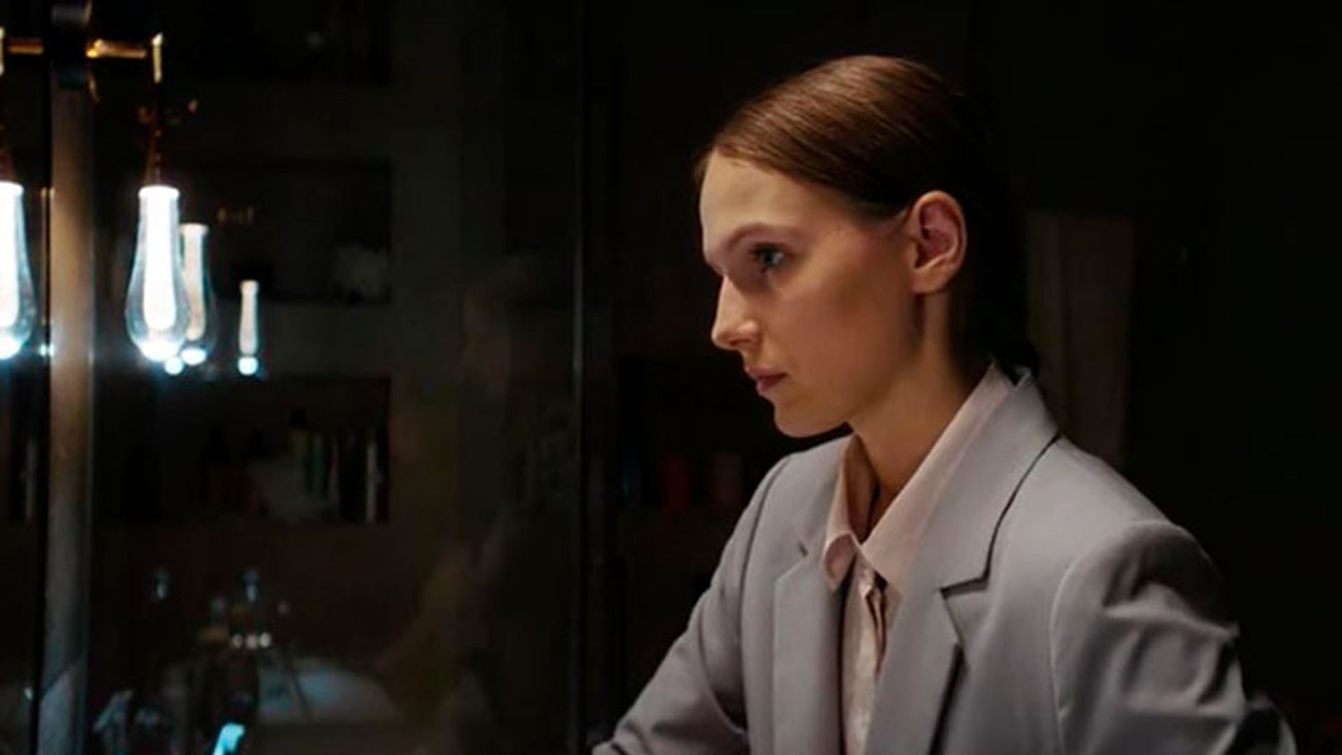 Маруся Фомина с пучком и в светлом пиджаке, вид сбоку