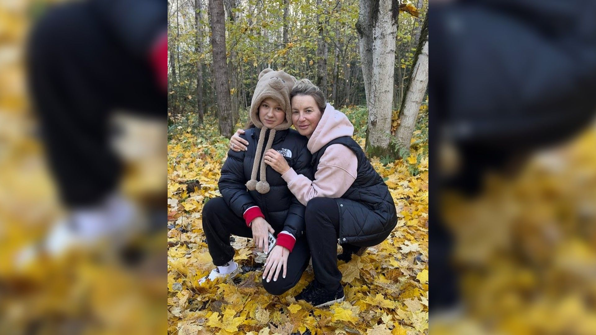 Ирина Слуцкая и её дочь сидят на корточках в жёлтой листве