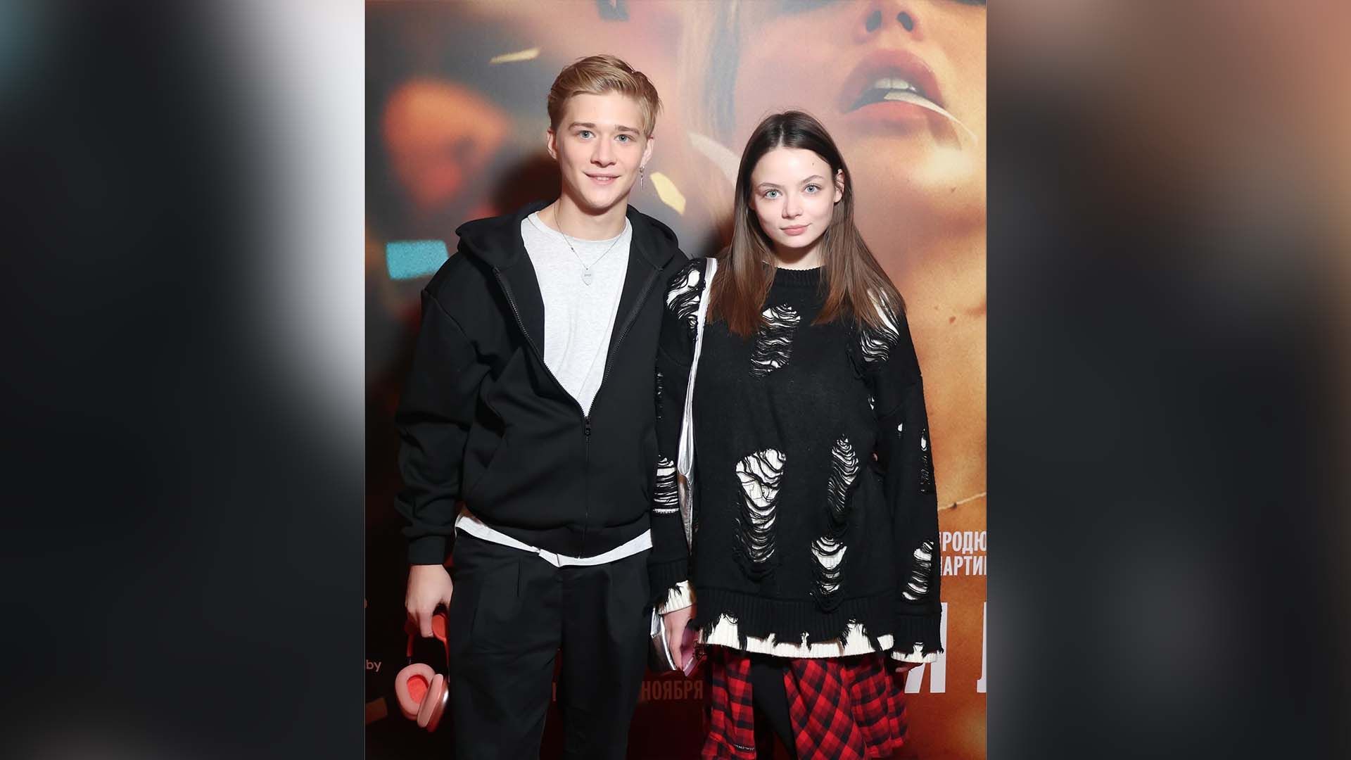 Олег Савостюк и Ульяна Молдованова позируют на фоне постера фильма