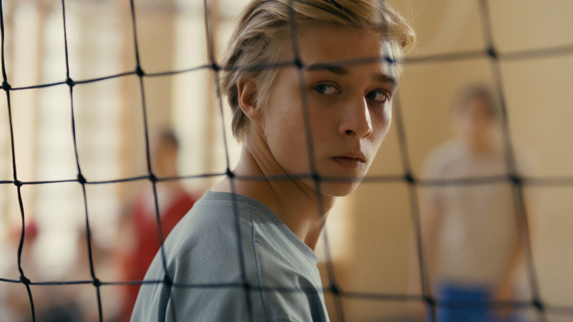 Олег Савостюк, снятый сквозь волейбольную сетку, смотрит через плечо