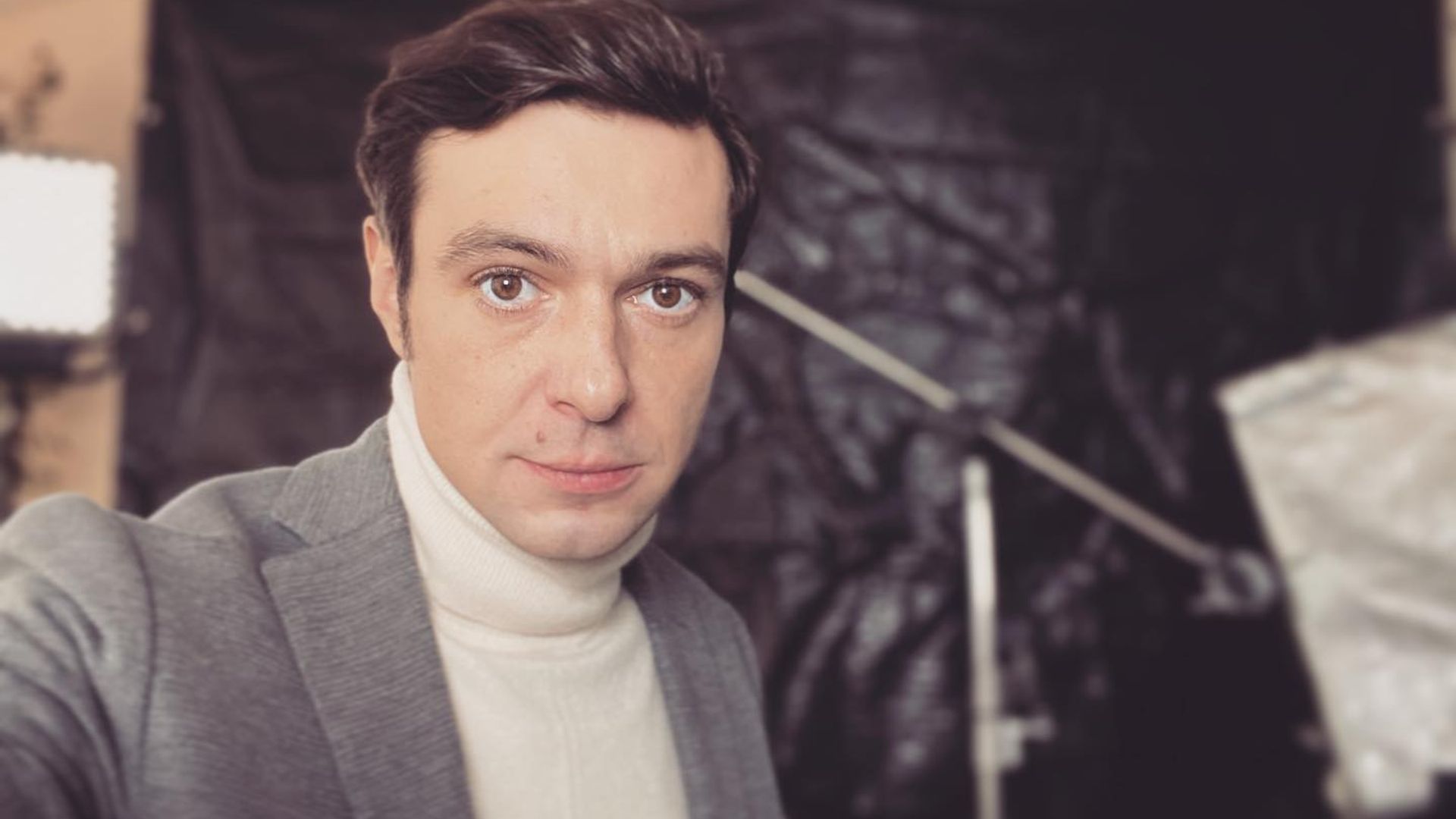 Павел Баршак в костюме и с прилизанными волосами делает селфи