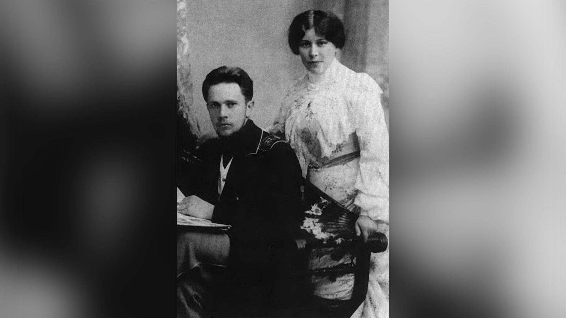 Алексей Толстой сидит на стуле, за его спиной стоит его первая жена Юлия Рожанская