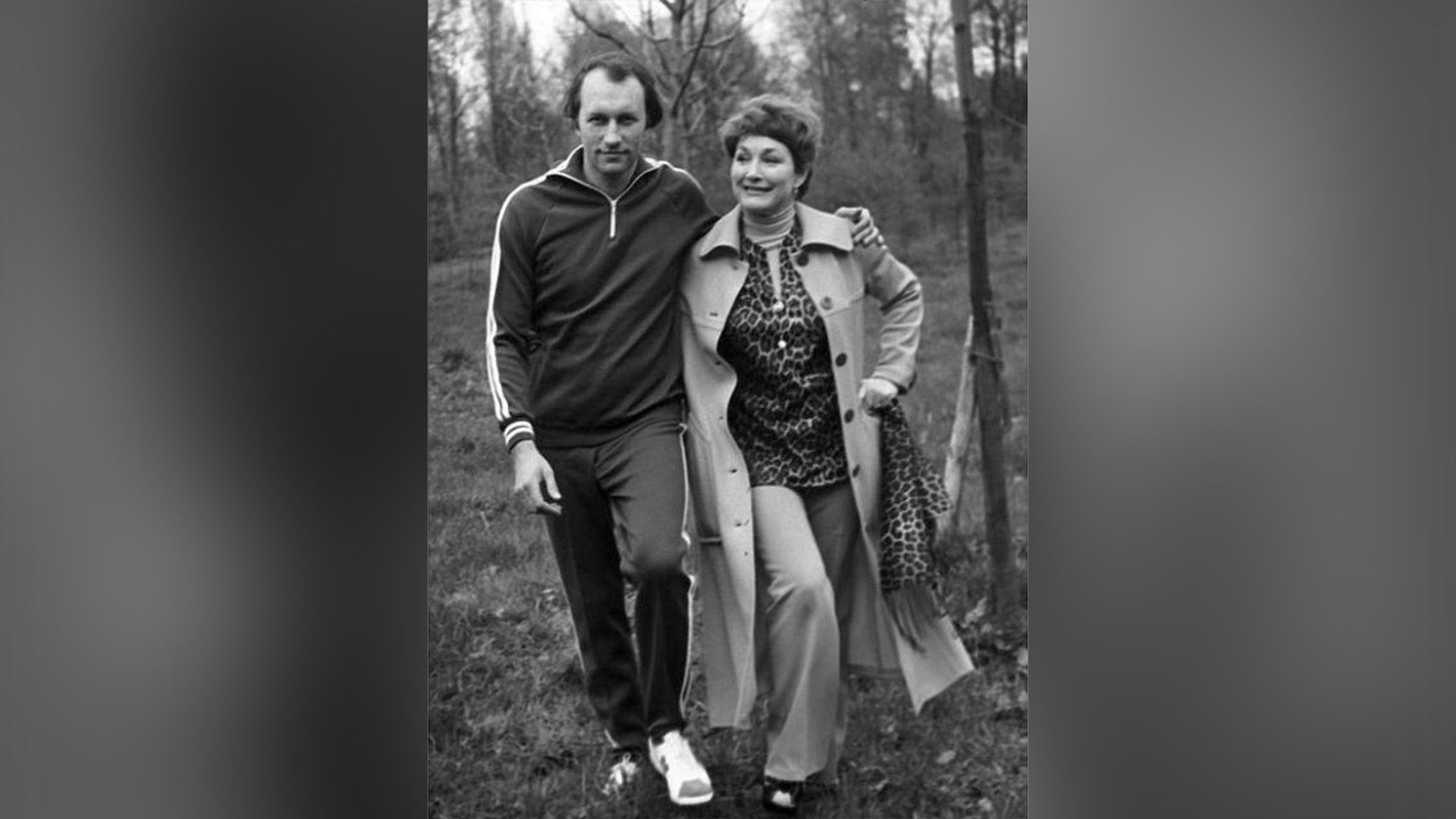 Мужчина в спортивном костюме и женщина в плаще в лесу