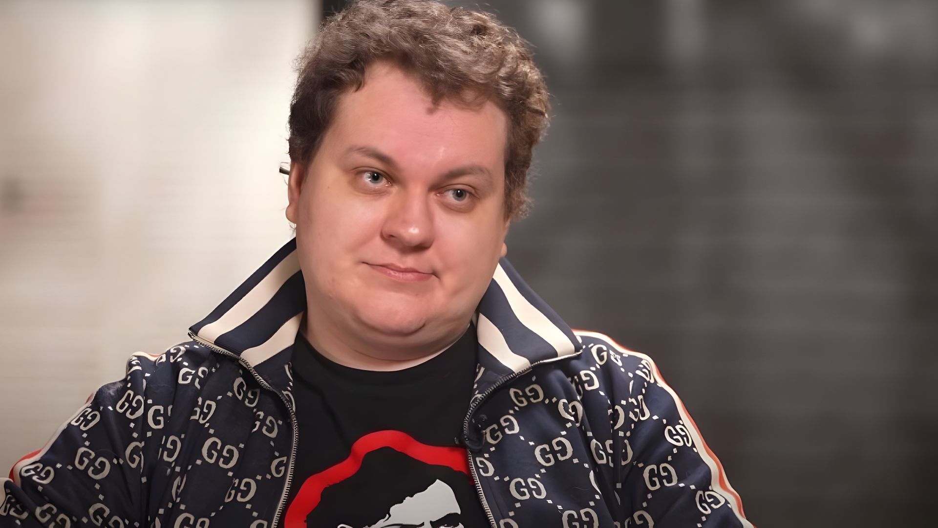 Блогер Юрий Хованский, лицо крупным планом, кудрявые волосы, на нём куртка от Gucci