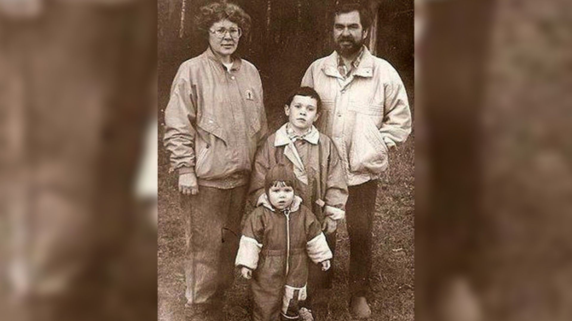 Старая чёрно-белая фотография семьи: родители и двое детей (девочка - певица Дина Гарипова в детстве) позируют на улице в осенней одежде