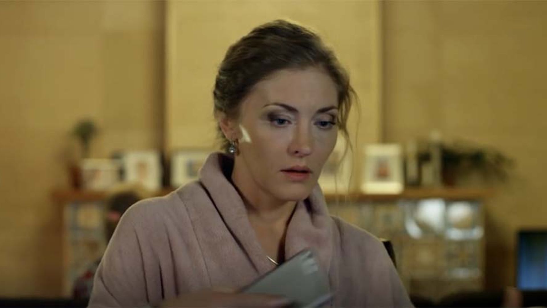 Анна Казючиц в халате выглядит встревоженной, держит в руках что-то, с серьезным выражением лица
