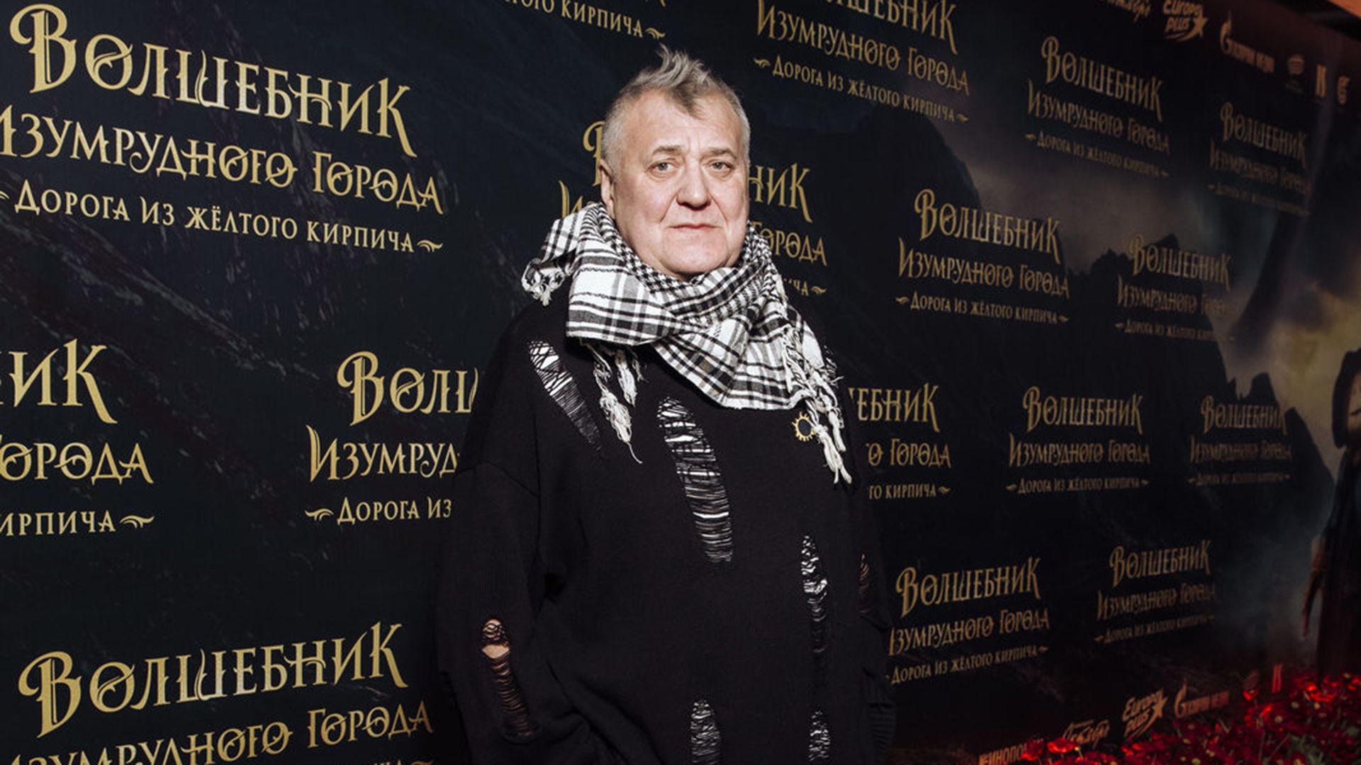 Актёр Артур Ваха в чёрном свитере и с клетчатым платком на шее