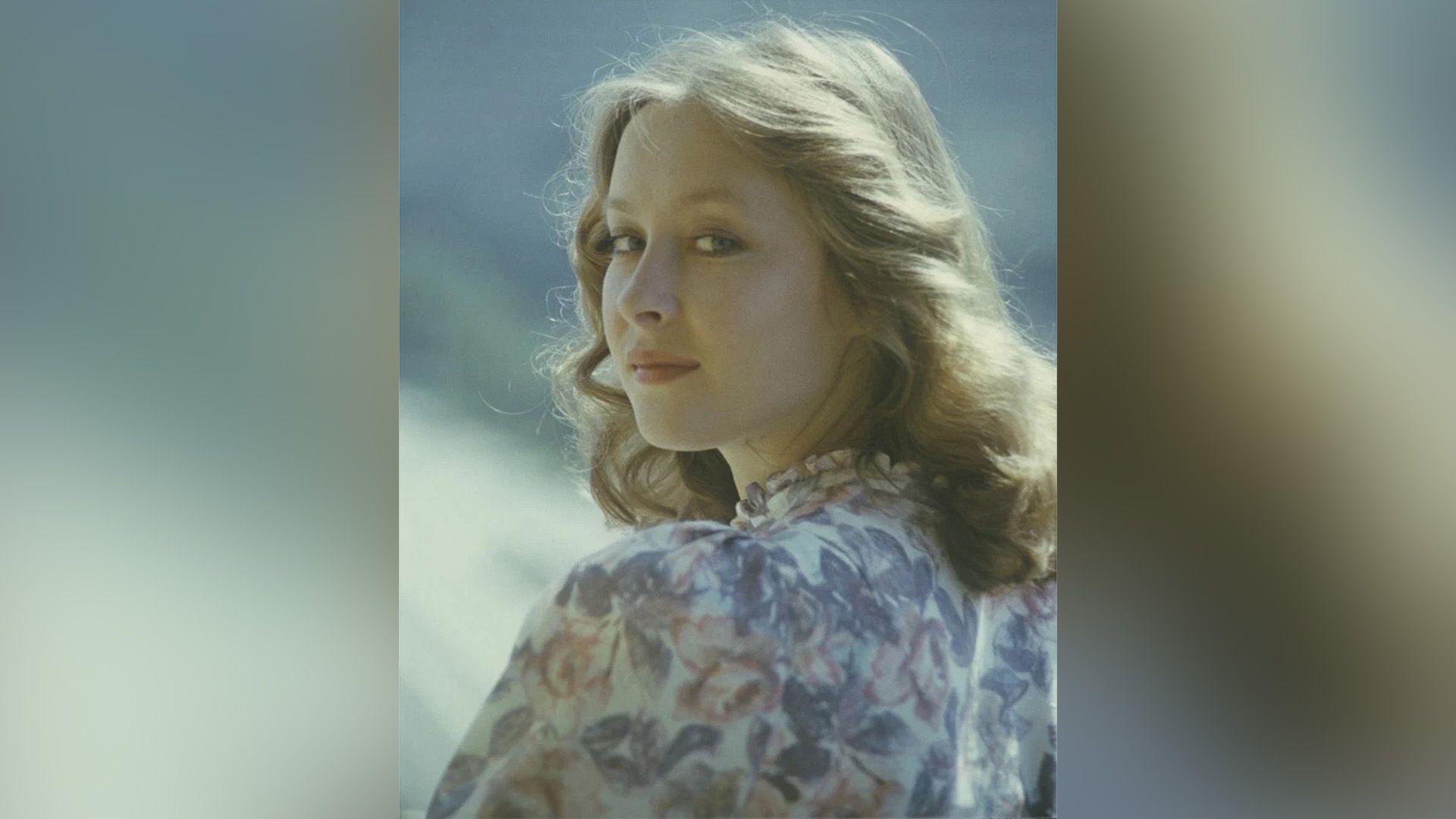 Молодая Лариса Удовиченко в платье в цветочек смотрит через плечо
