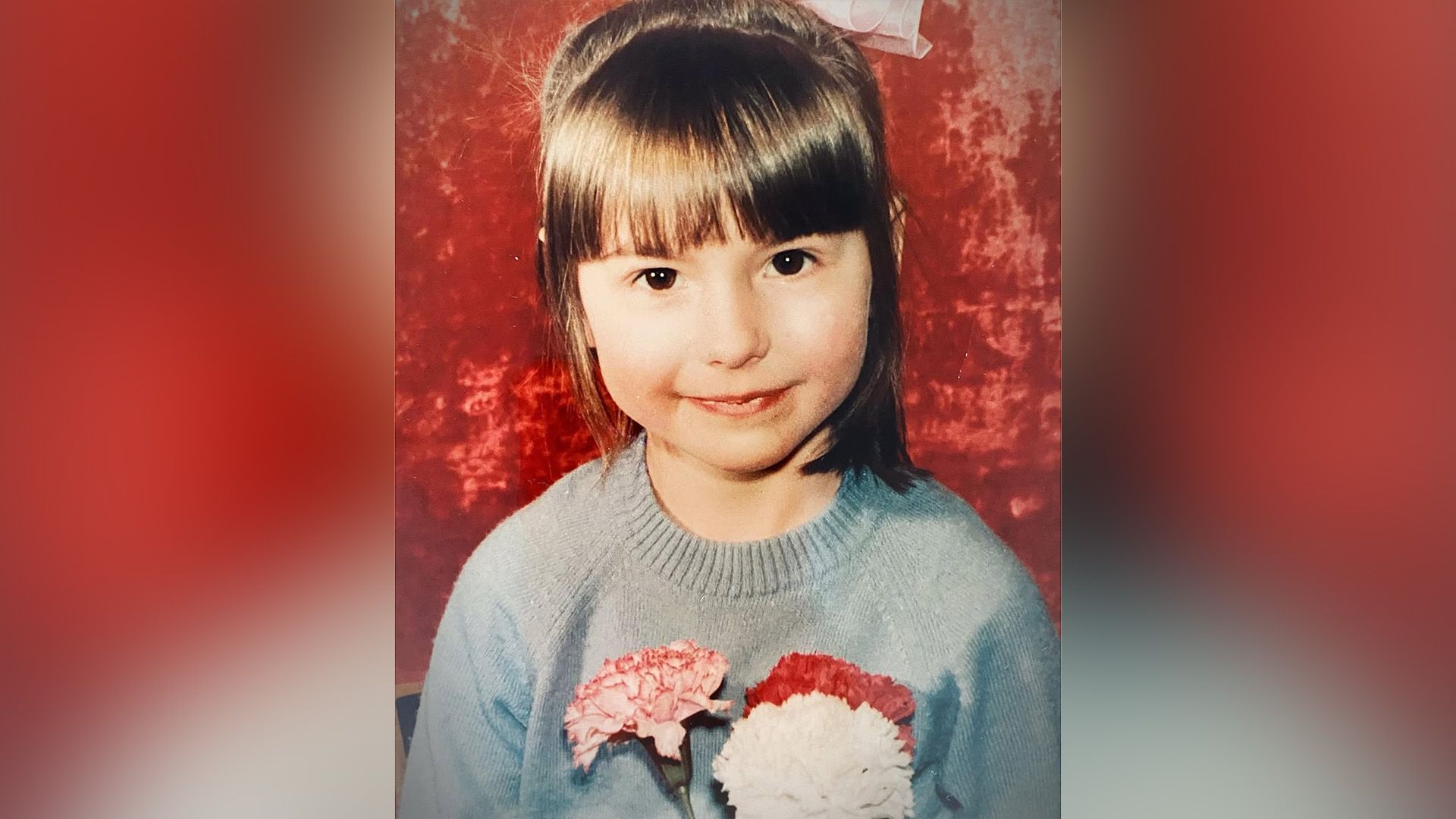 Ирина Ефремова в детстве в сером свитере и с цветами в руках