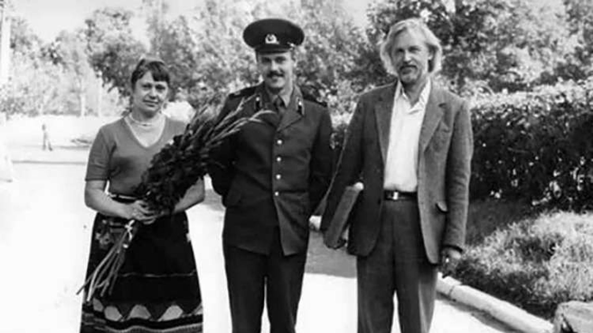 Женщина с букетом, мужчина в форме и Станислав Любщин в костюме стоят на улице