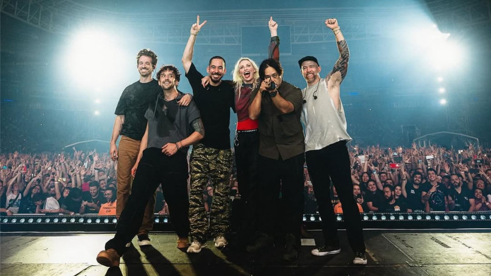 Участники группы «Linkin Park» улыбаются на сцене на фоне зрителей