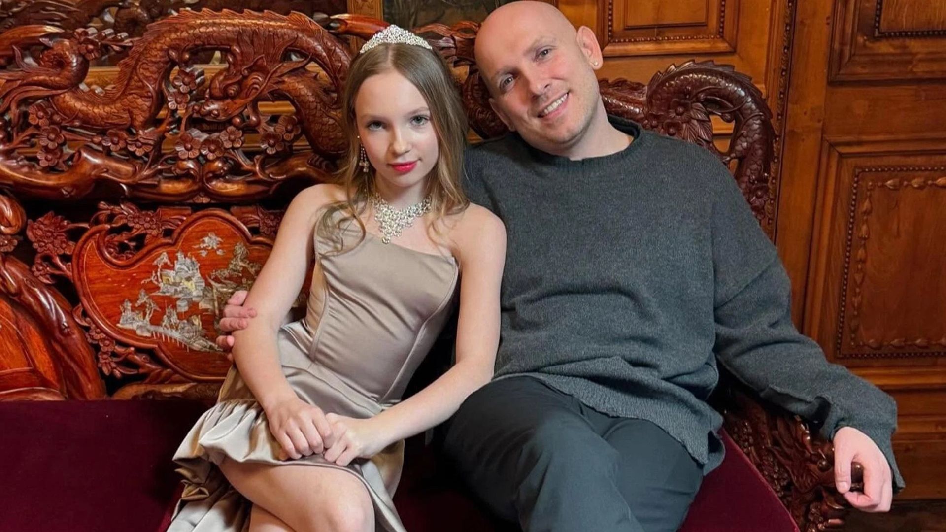 Светлана Чертищева в нарядном бежевом платье и Александр Чертищев в сером свитере сидят на диване