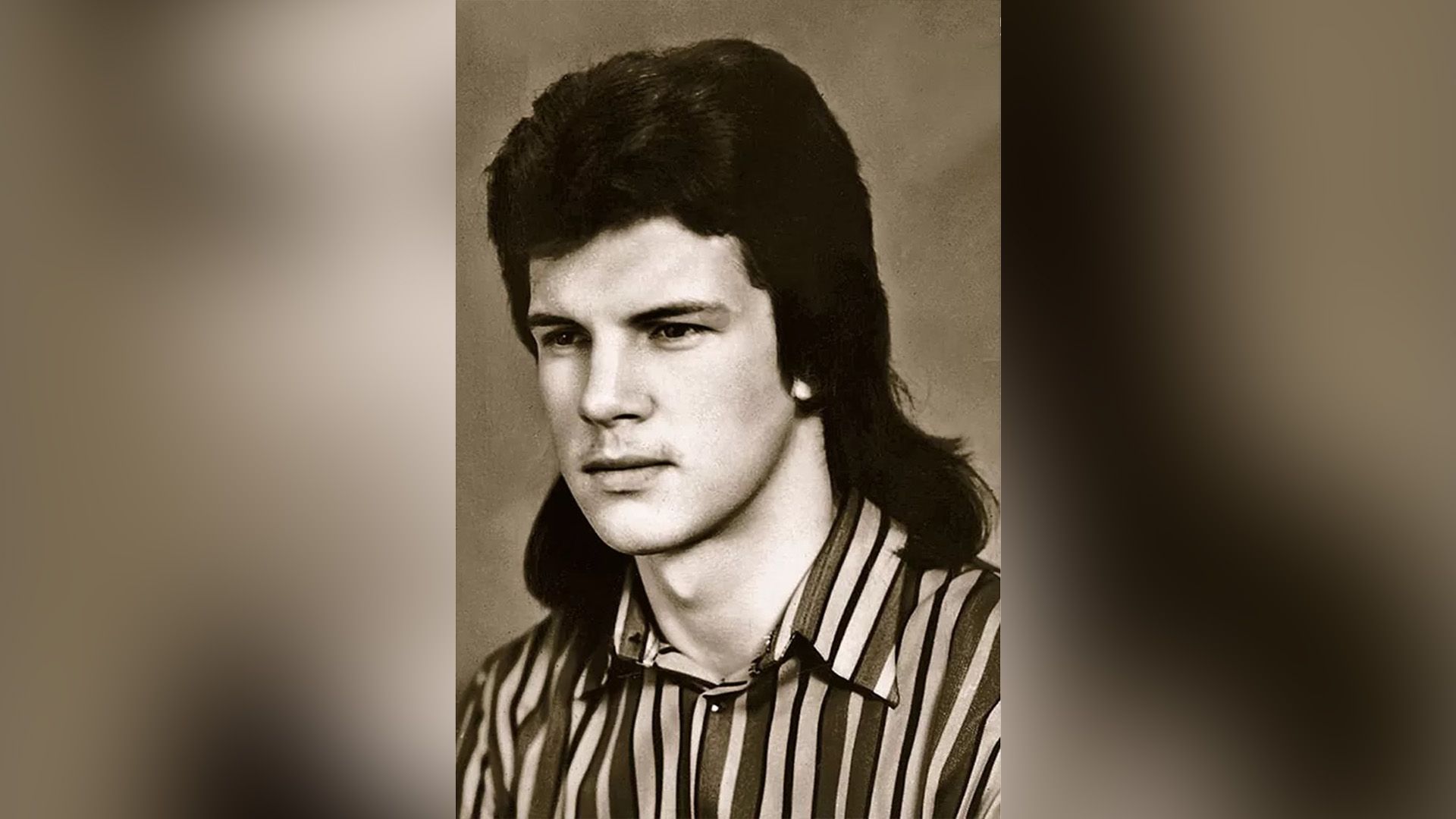 Молодой актёр Анатолий Котенёв с длинными волосами и в полосатой рубашке