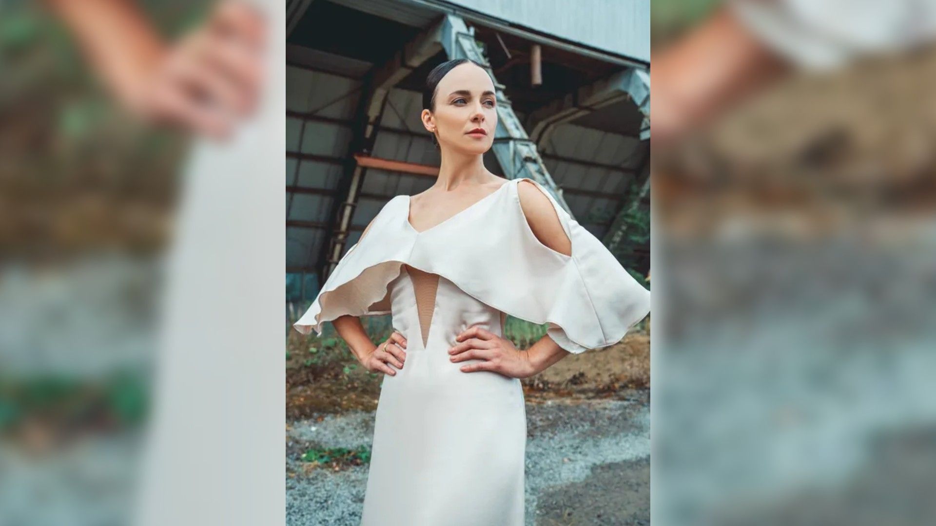 Анна Снаткина в светлом платье с открытыми плечами позирует на фоне заброшенного промышленного здания