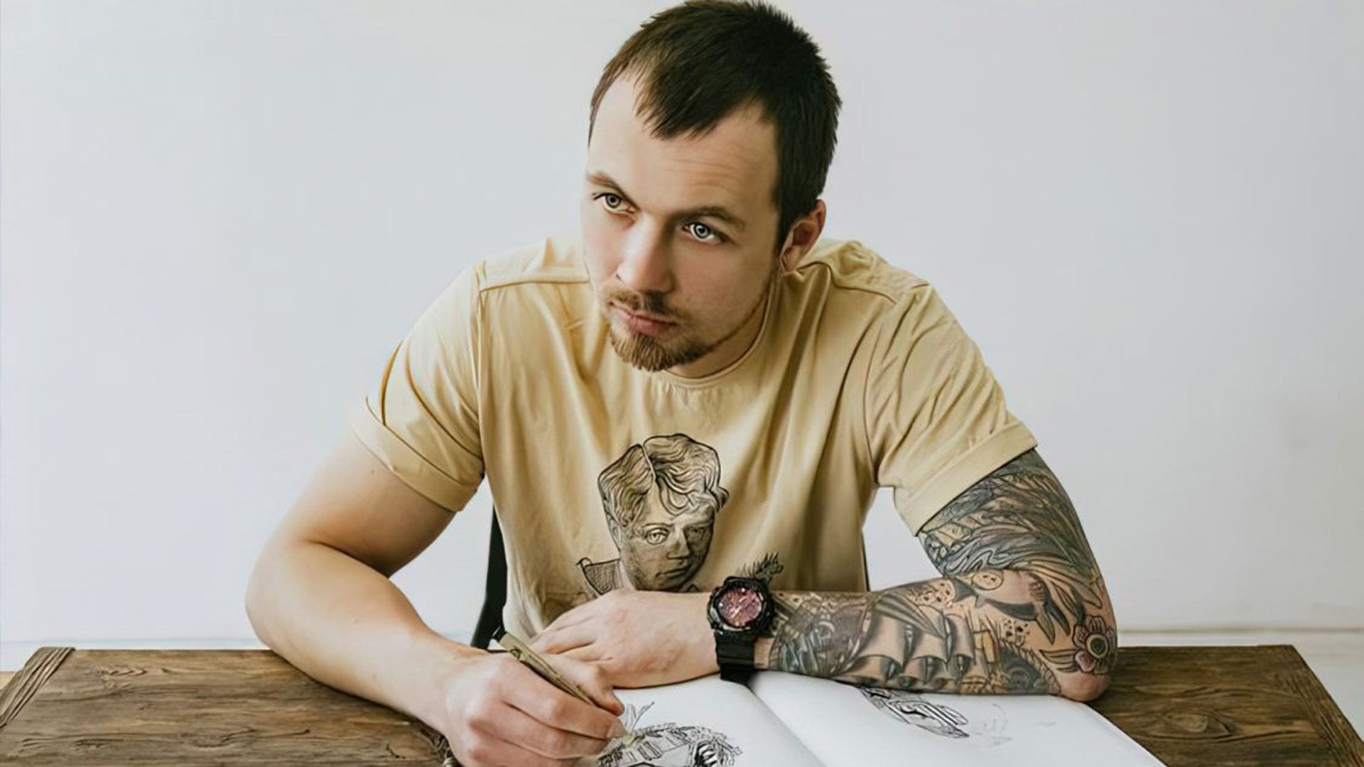 Сын Александра Скляра Пётр в жёлтой футболке сидит за столом и рисует в альбоме