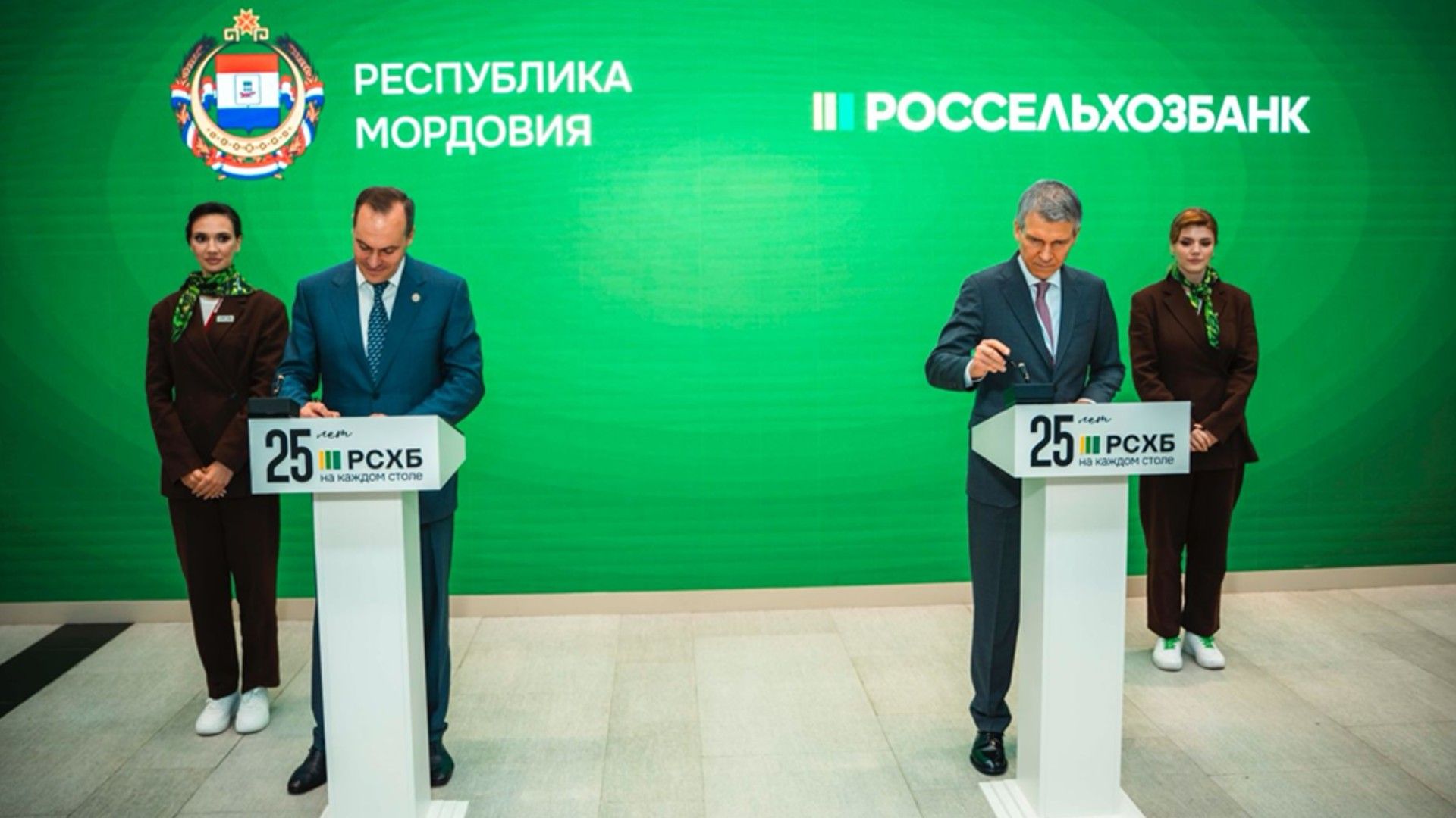 Официальная церемония подписания между представителями Республики Мордовия и Россельхозбанка на фоне зелёного экрана с логотипами.