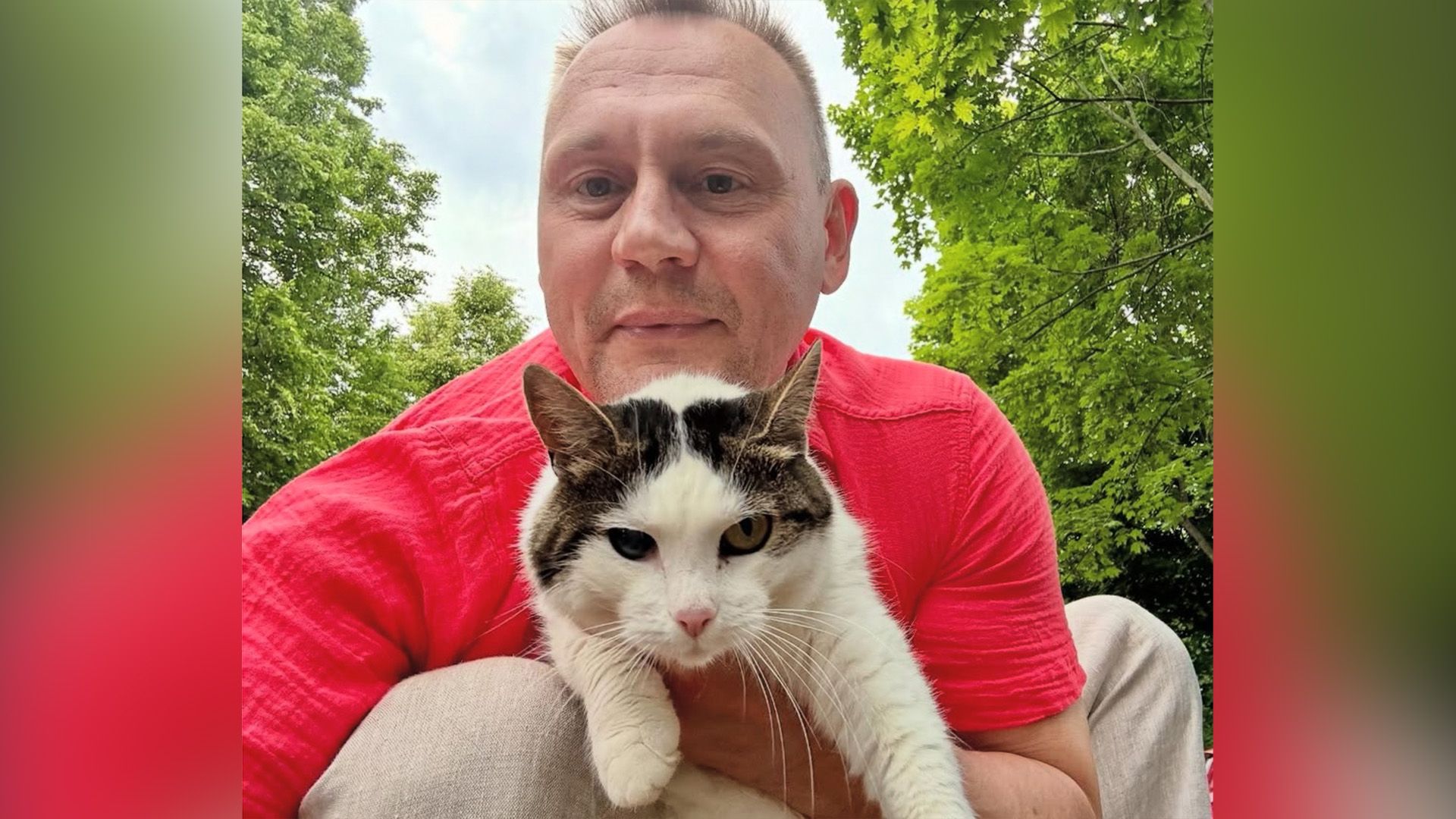 Степан Меньщиков в красной футболке держит в руках чёрно-белую кошку