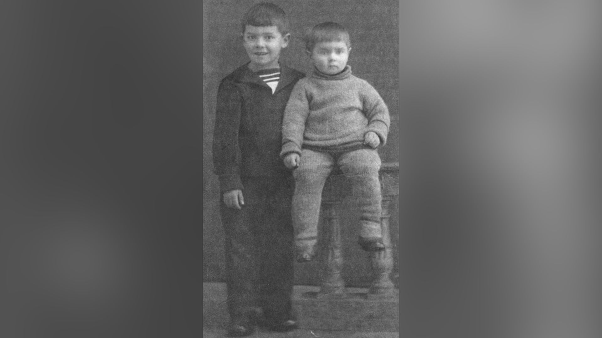 Юрий Любимов в детстве сидит на деревянных перилах, рядом стоит его старший брат Давид