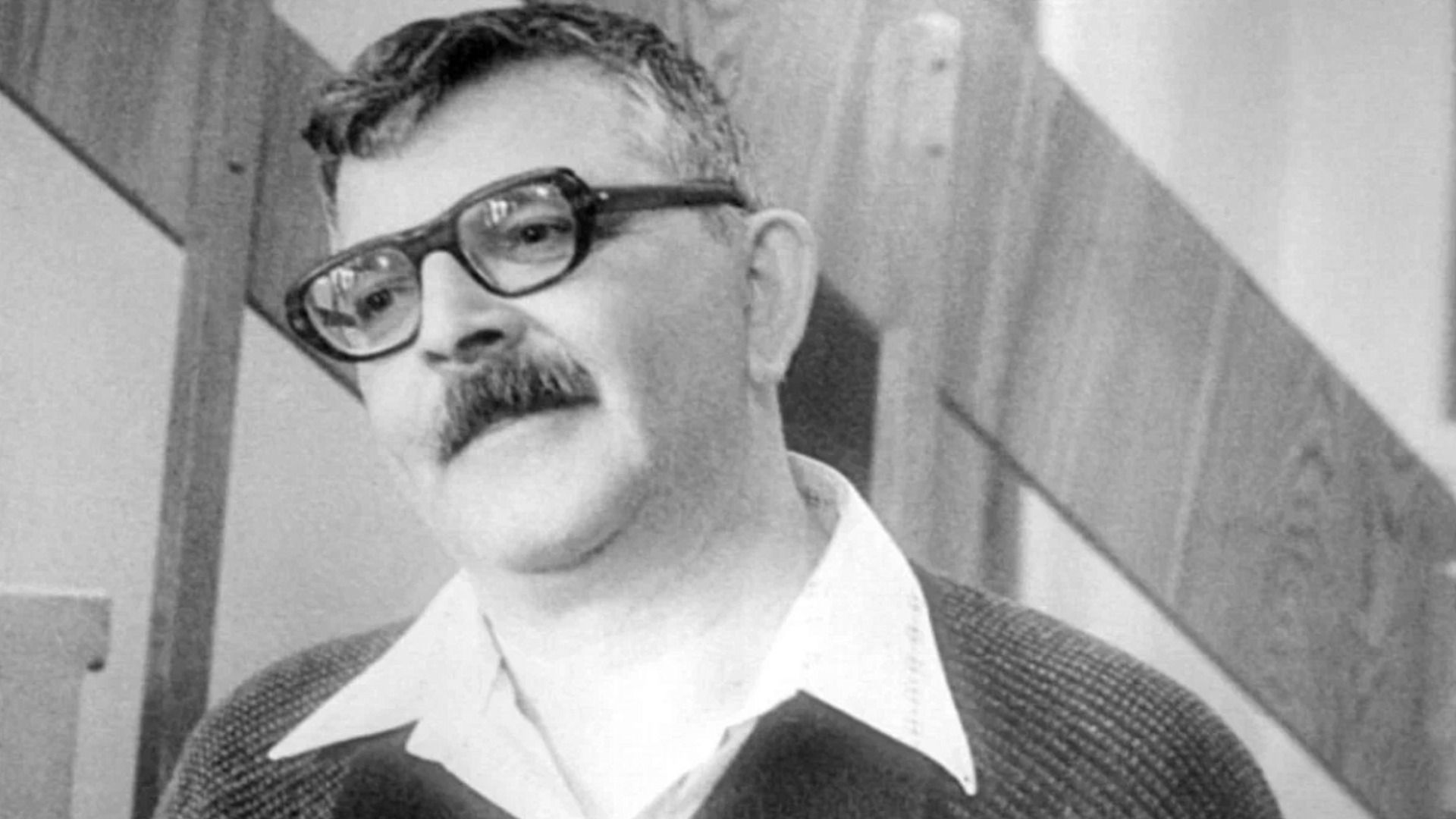 Писатель Аркадий Стругацкий в очках стоит рядом с лестницей
