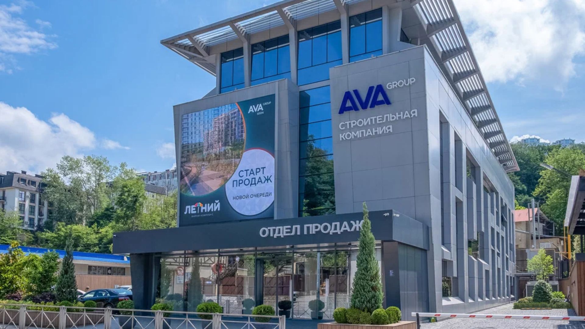 Серое здание с большими окнами, на фасаде вывеска "AVA Group строительная компания"